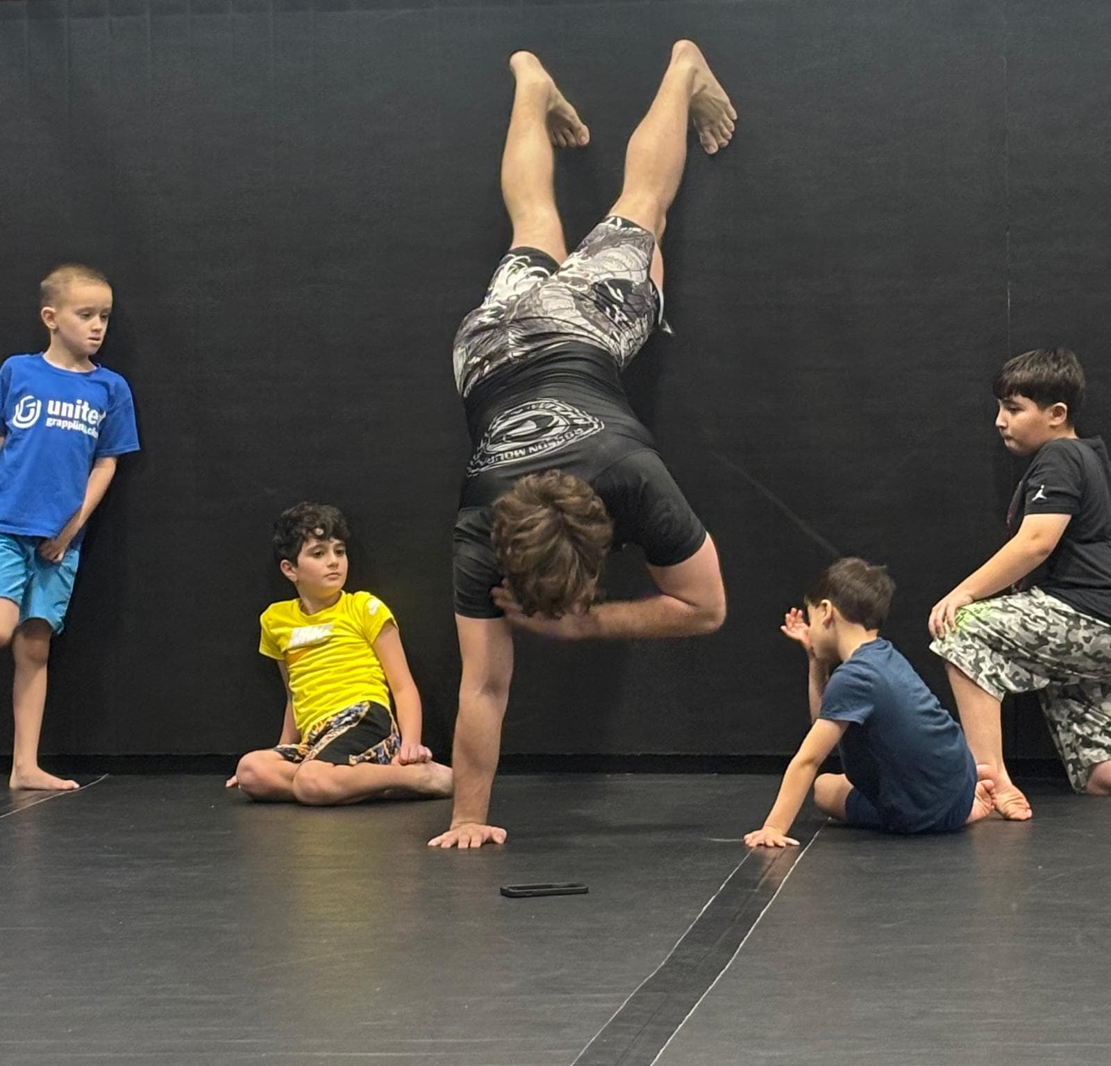 Coach demonstrating a movement while kids watch at United Grappling Club